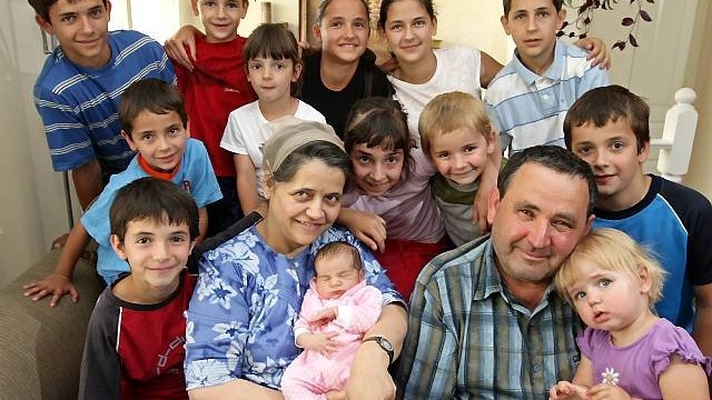 Livia Ionce, 44, second left, holds her newborn daughter, Abigail Ionce, who was born Tuesday, as she and her husband, Alexandru, 51, pose for a photograph with 13 of their 18 children at their home in Abbotsford, Canada on Saturday July 26, 2008. Their oldest child is 23-years-old. The couple immigrated to Canada from Romania in 1990. (AP Photo/The Canadian Press, Darryl Dyck)